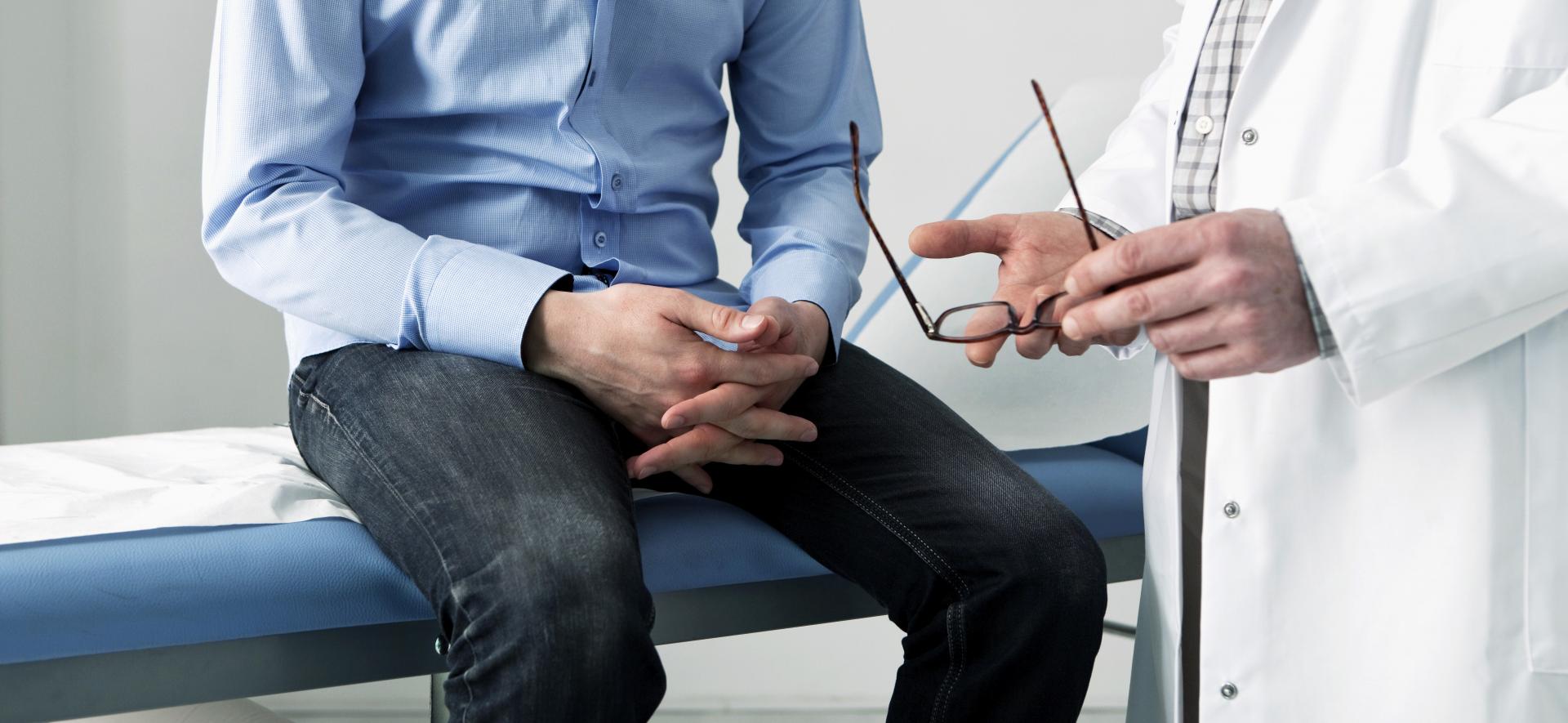 Ein Mann sitzt auf der Untersuchungsliege beim Arzt und lässt sich von seinem Arzt beraten