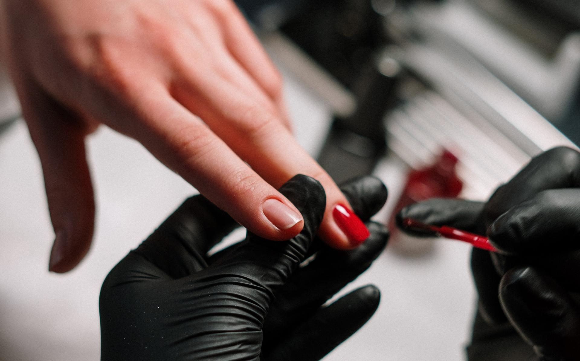 Eine Frau ist im Nagelstudio und lässt sich ihre Nägel neu lackieren. Dafür können UV-Lampen verwendet werden, die negative 