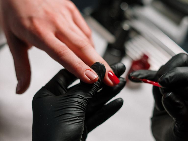 Eine Frau ist im Nagelstudio und lässt sich ihre Nägel neu lackieren. Dafür können UV-Lampen verwendet werden, die negative 