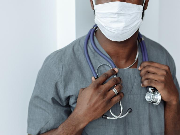 Ein Arzt hält sein Stetoskop in den Händen und ist selbstbewusst