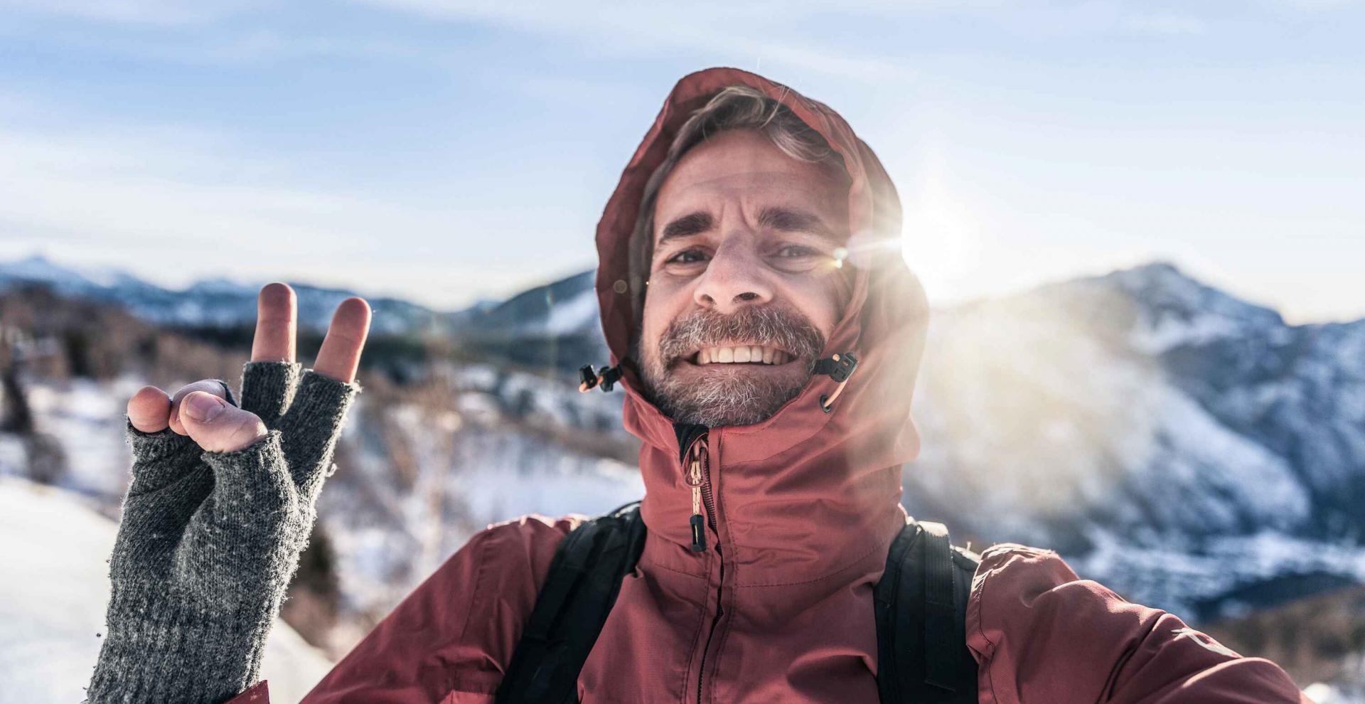 Ein Mann mittleren Alters ist in den Bergen wandern und macht ein Selfie in den Bergen.
